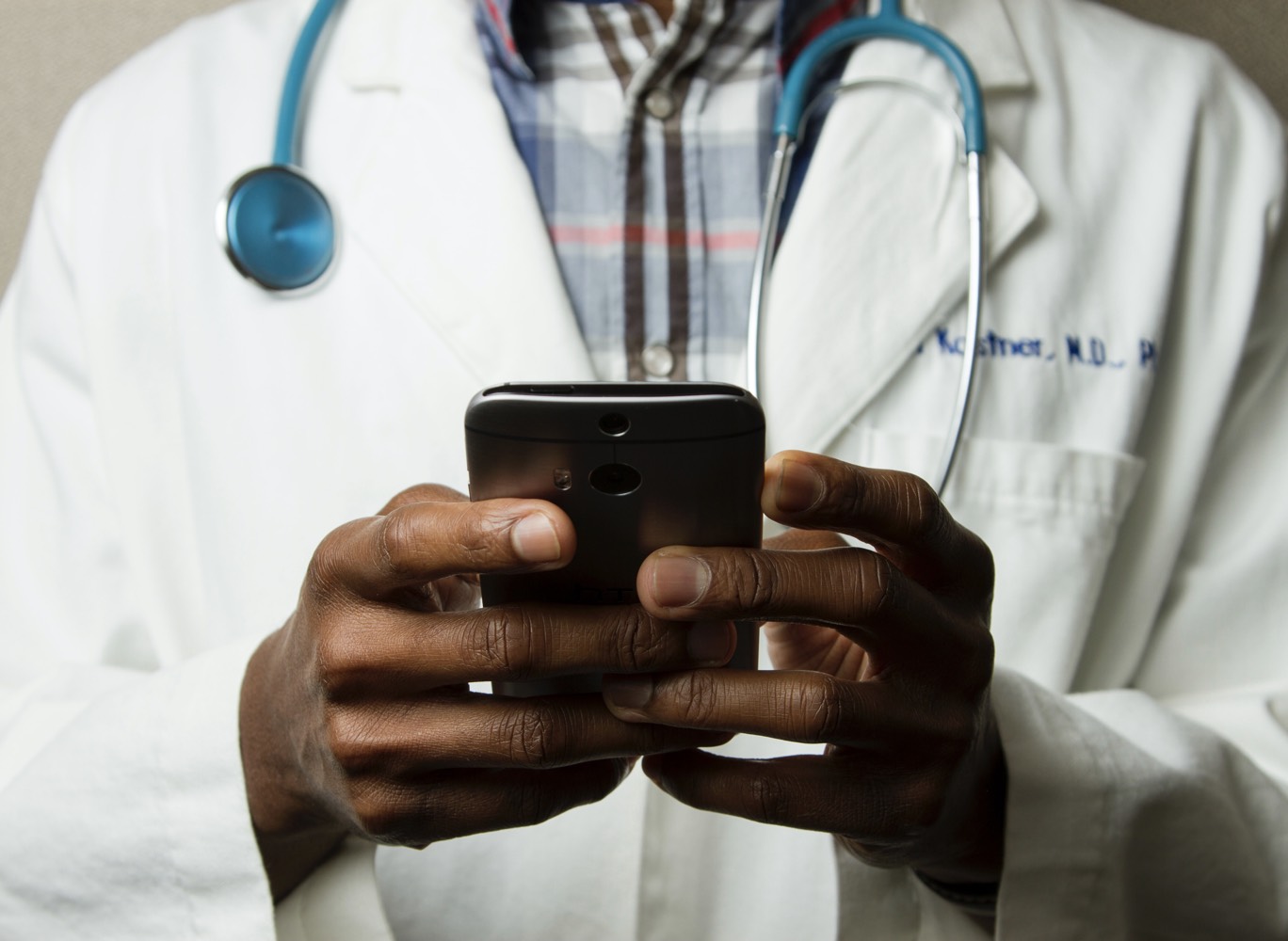 A doctor holding a smart phone with two hands